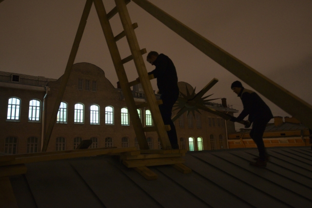 Рабочие на крыше церкви Святой Анны поднимают крест на купол