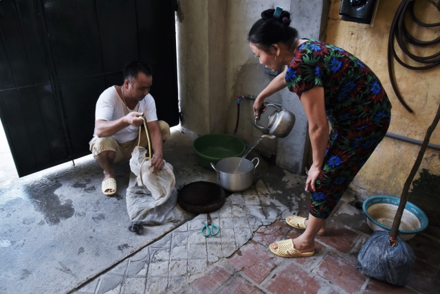 Для быстрого снятия чешуи, змей обрабатывают кипятком. Thi Hue помогает мужу перед тем, как заняться на кухне приготовлением змеиных блюд. Винь Сон. Вьетнам