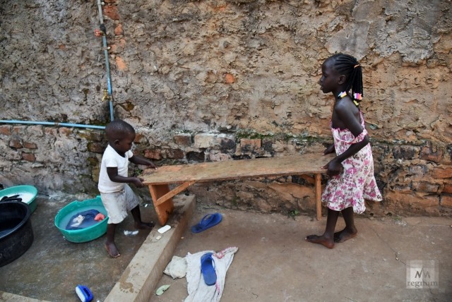 Марта (7 лет) и Сандэй (3 года) переносят скамейку, чтобы обустроить себе место для стирки одежды. Window of Life, Масинди, Уганда