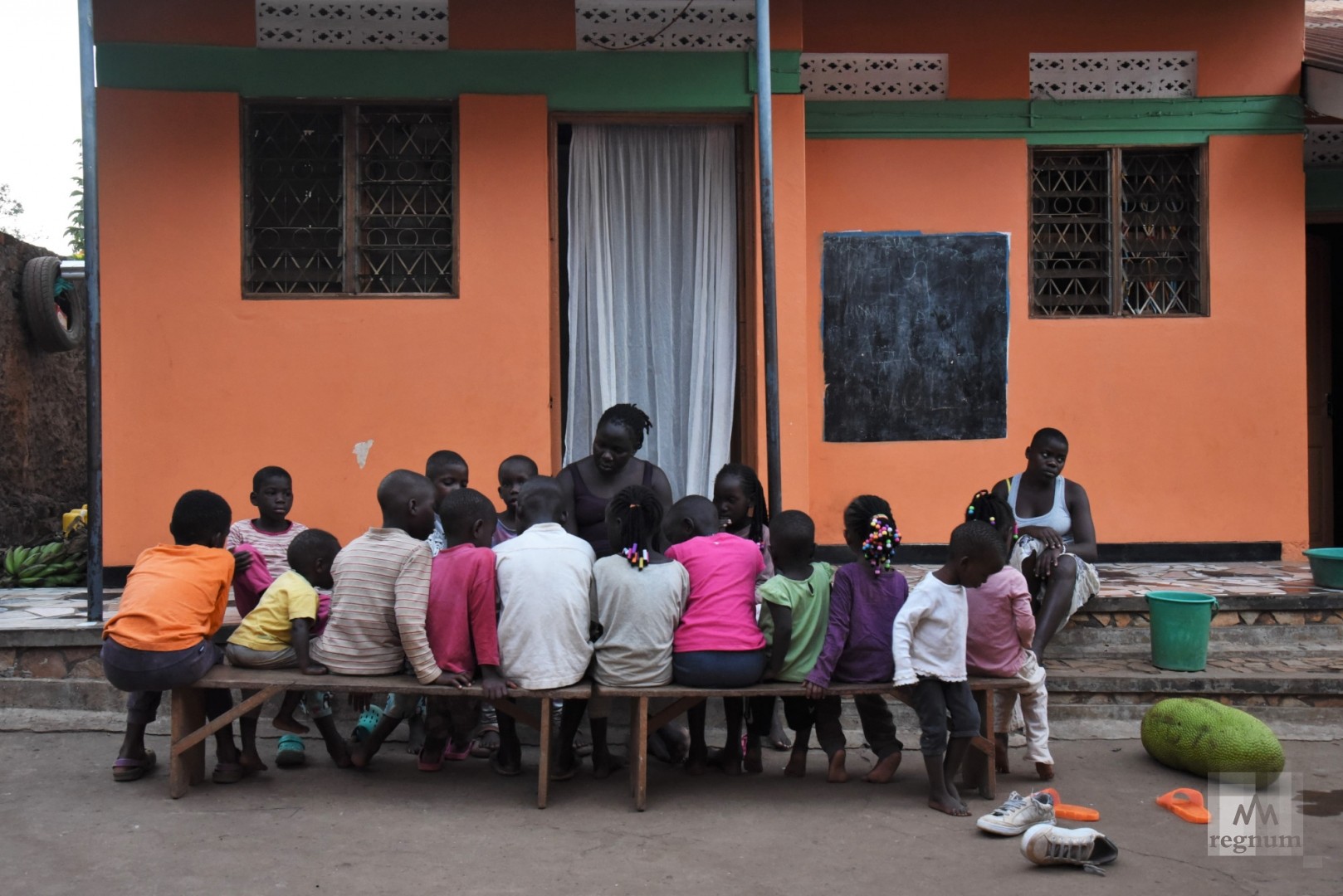 Мария читает детям книгу во дворе Window of Life.  Масинди, Уганда
