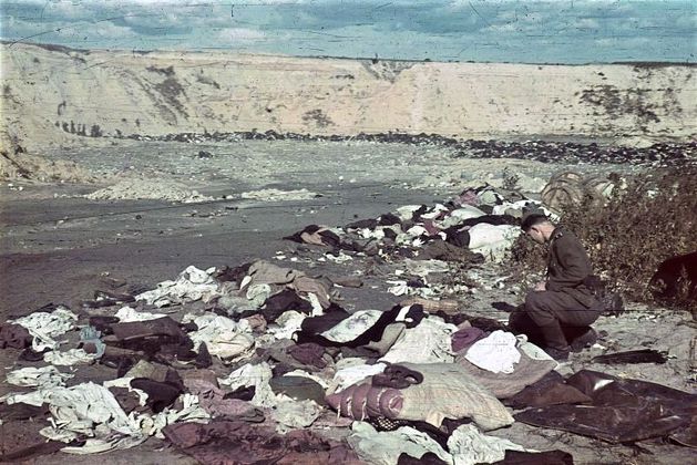 Эсэсовец роется в вещах расстрелянных в урочище Бабий Яр. 1943 год